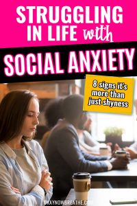 Female alone at table with a crowded table next to here. She's looking down. Text says struggling in life with social anxiety: 8 signs it's more than just shyness