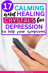 There is a person holding a black crystal point. Above that image, there is text that says: 17 calming and healing crystals for depression to help your symptoms - okaynowbreathe.com