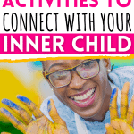 A Black woman with glasses is smiling at the camera with both palms out and facing the camera. She has yellow and blue finger paint on her palms. Text overlay says, "13 nostalgic activities to connect with your inner child - okaynowbreathe.com"