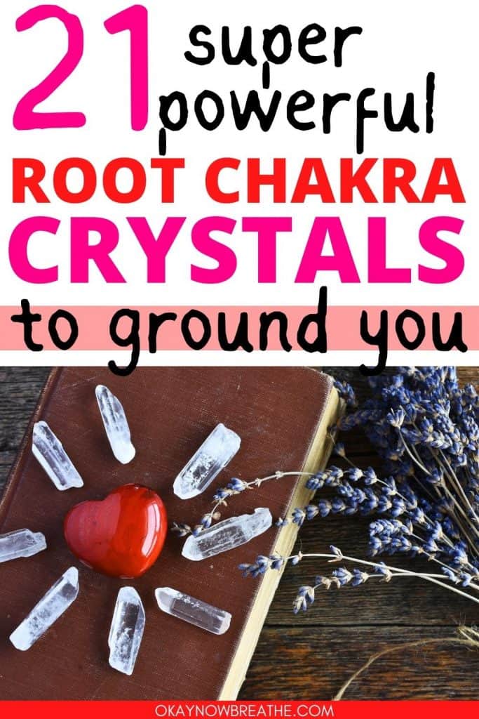 There is a red crystal in the shape of a heart on a brown notebook. Surrounding the red crystal are clear quartz crystal points. To the side, there are lavender stems. Above this image, text says: 21 super powerful root chakra crystals to ground you - okaynowbreathe.com